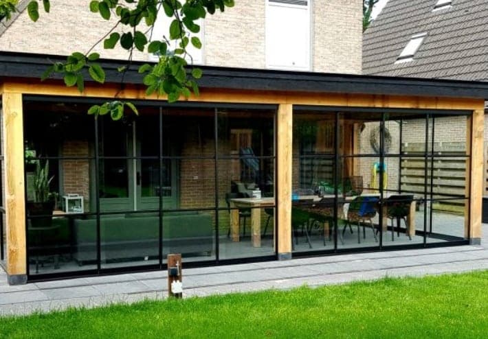 Ingerichte glazen veranda met houten balken aan een woning