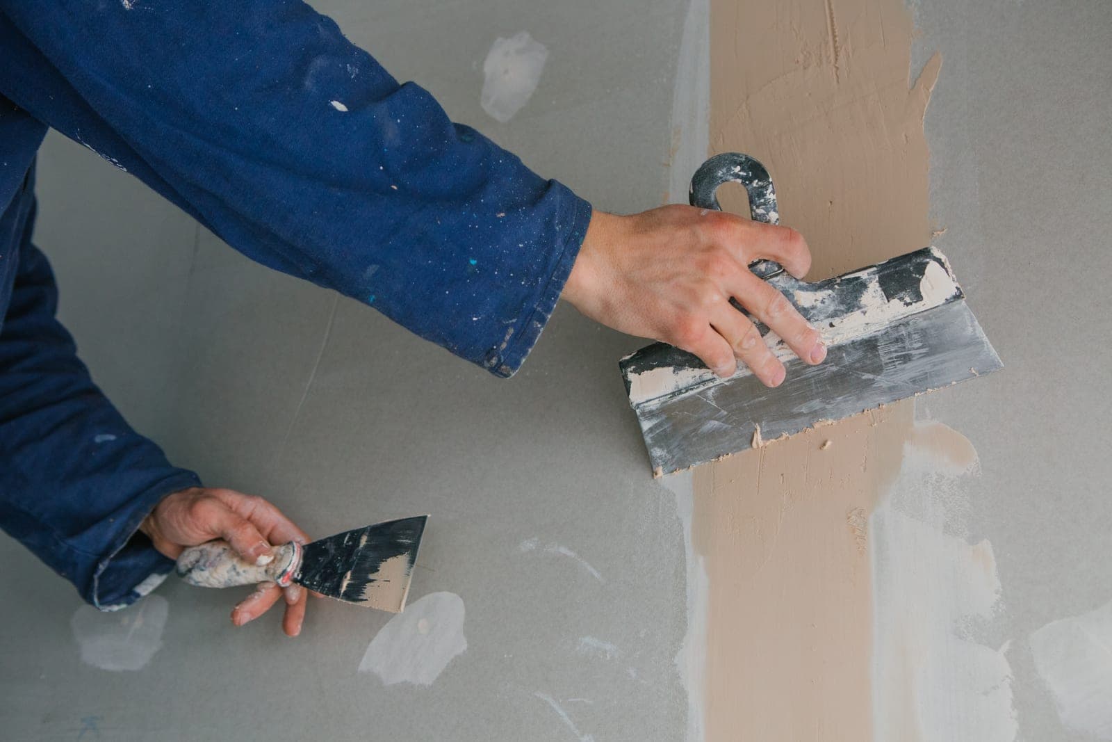 Stukadoor die met twee troffels een wand pleistert